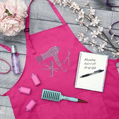 a pink apron with writing on it next to flowers and other items that include scissors