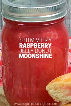 a jar of raspberry jelly with a half eaten doughnut