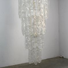 a chandelier made out of plastic bottles hanging from the ceiling in an empty room