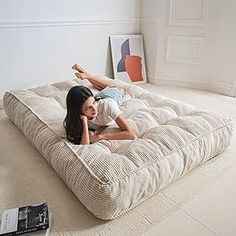 a woman laying on top of a large mattress