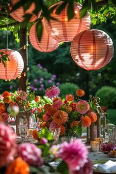 the table is set with pink and orange flowers in vases, lanterns and candles