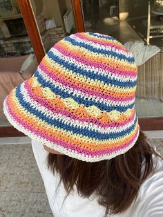 a woman wearing a multicolored crocheted hat looking out the window at something outside