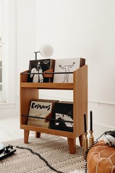 a wooden shelf with books and magazines on it in a room next to a lamp