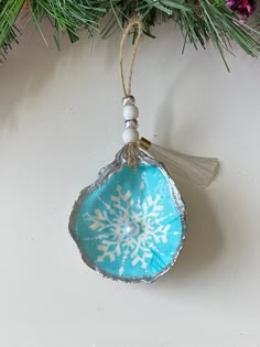 a blue ornament hanging from a christmas tree with snowflakes on it