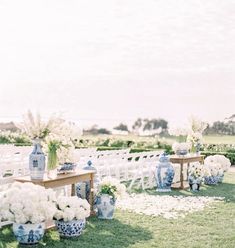 an outdoor ceremony setup with white flowers and blue vases on the side of the aisle