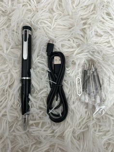 a pen and some other items laying on a white blanket with the cord plugged in