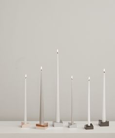 five white candles are lined up in a row with one candle on the other side