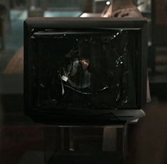 an old tv sitting on top of a table in front of a person with their foot up