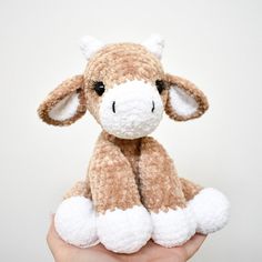 a hand holding a small stuffed animal in it's left hand, with one eye open