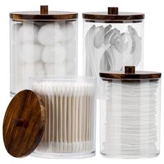 three clear containers with wooden lids and white plastic objects in them on a white background