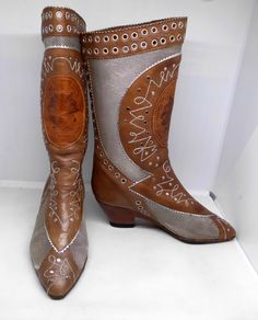 Offered for sale is this exceptional pair of custom-made, Bohemian chic, El Vaquero mid-calf boots combining silver metallic mesh, brown leather, probably aged, silver studs, eyelet work, and silver metallic embroidery and stitching. The pair is pre-owned, gently worn, must be slipped on, are a Size 7 or 39.5, and are hand-made in Italy. Valerio Giuntoli, the brilliant designer and creator of these shoes began making custom-made Italian boots and women's footwear in 1975 and the El Vaquero brand History Knowledge, Italian Boots, Metallic Mesh, Metallic Embroidery, Calf Boots, Modern Bohemian, Embroidery And Stitching, Women's Footwear, Mid Calf Boots