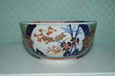 a white and blue bowl sitting on top of a counter next to a green wall