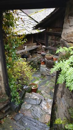 an old stone house with potted plants in the yard