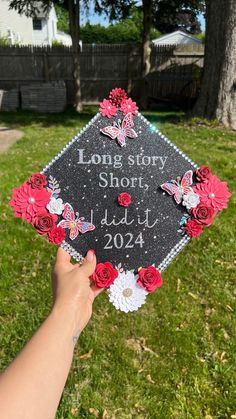 someone holding up a graduation cap with flowers on it