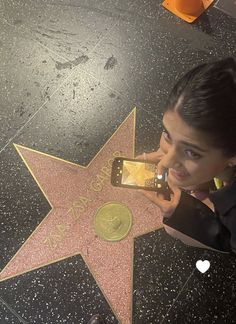 a woman taking a selfie with her cell phone on the hollywood walk of fame