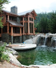 a large wooden house sitting on top of a lush green hillside next to a river