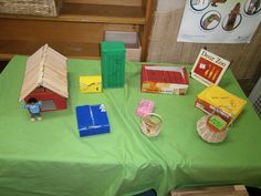 a table topped with books and toys on top of a green cloth covered tablecloth