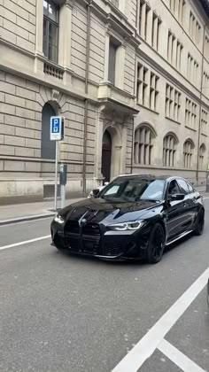 a black car is parked on the side of the road in front of an old building