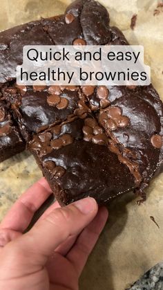 a person holding up some brownies with chocolate chips on top and the words quick and easy healthy brownies above it