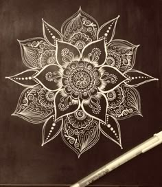 a pen sitting on top of a blackboard with an intricate flower drawn on it