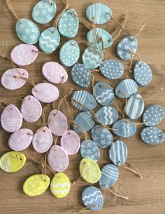 several different colored ceramic hearts hanging from twine on a wooden table with jute string