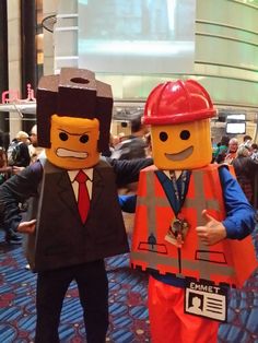 two people in lego costumes standing next to each other with their thumbs up and one wearing a red hard hat