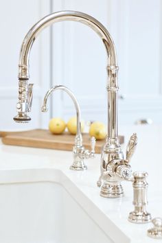 a kitchen sink with two faucets and some lemons on the counter top