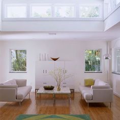 a living room filled with white furniture and lots of windows