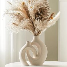 a white vase with some dried plants in it