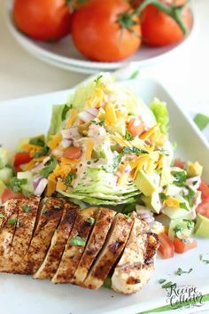 grilled chicken, lettuce and tomato salad on a white plate