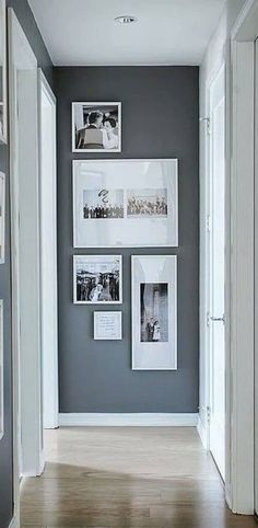 a hallway with pictures on the wall and wooden floors in front of it, along with white framed photos