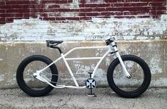 a white bicycle parked next to a brick wall