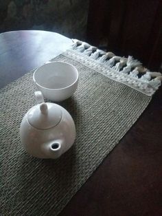 two white bowls sitting on top of a wooden table next to a bowl and saucer