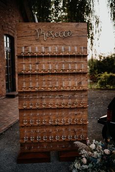 a wooden sign with glasses on it sitting in front of a brick building next to flowers