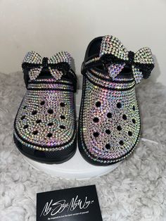 MyStyleMyWay's  custom crocs are designed for the perfect outfit, that special occasion, and "Just Because" you love blinged out crocs.  In the display shown we designed a pair of black classic crocs adding high quality colorful rhinestones. 🎀 Each Rhinestone is individually and neatly placed to achieve the design.  🎀Rhinestones are added to the top portion of the shoe 🎀Bows are applied to the sports mode strap to this design to add cuteness and personality.  🎀This design do not have charms, charms can be added please contact us directly or visit our website www.MyStyleMyWay.co to view our charm selection.  🎀When making your purchase - You're making a purchase for the exact style shown. If you would like a different color rhinestone,  and or different charms please message us so we ca Blinged Out Crocs, Crocs Custom, Bedazzled Crocs, Designer Crocs, Bling Crocs, Custom Crocs, Classic Crocs, Black Crocs, Pretty Sneakers