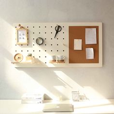 a white desk topped with lots of clutter next to a wall mounted bulletin board