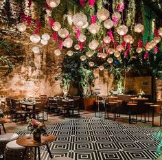 a room with tables, chairs and chandeliers hanging from the ceiling over them