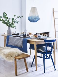 a dining room table with blue chairs and a rug on the floor next to it