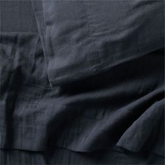 an unmade bed with dark blue linens and sheets on top of each other