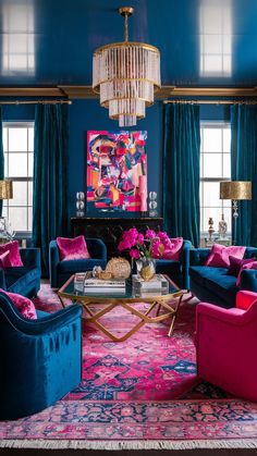 a living room with blue walls, pink and purple furniture and chandelier hanging from the ceiling