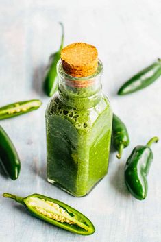 a jar filled with green stuff next to some peppers