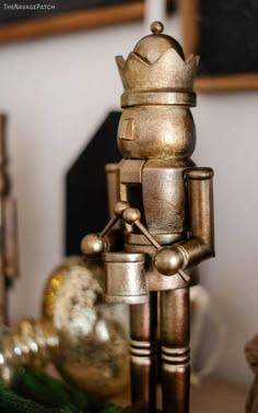 a metal robot statue sitting on top of a wooden table next to christmas tree ornaments