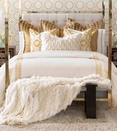 a white bed with gold pillows and blankets