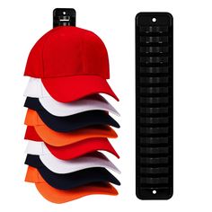 a stack of red, white and black baseball caps next to a rack of pins