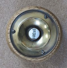 a metal object with the word press on it's center hole, sitting on a carpeted floor