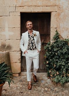 a man standing in front of a door wearing a white suit and flowered shirt