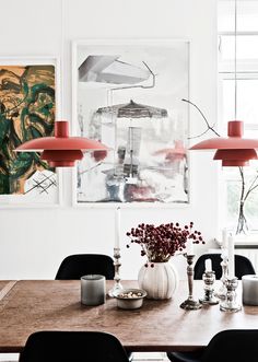 a dining room table with black chairs and two red lamps on the wall above it