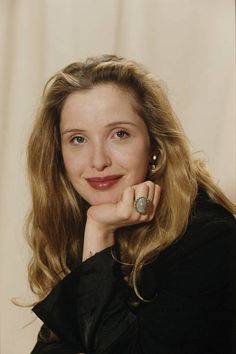 a woman with blonde hair wearing a black shirt and earrings, posing for a photo