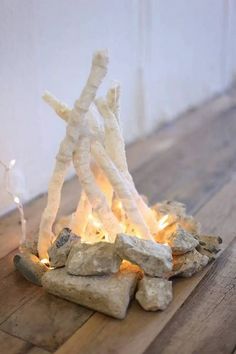 a fire pit made out of sticks and rocks on top of a wooden floor next to a wall