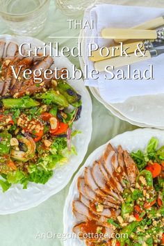 two white plates topped with salad and meat on top of a table next to utensils